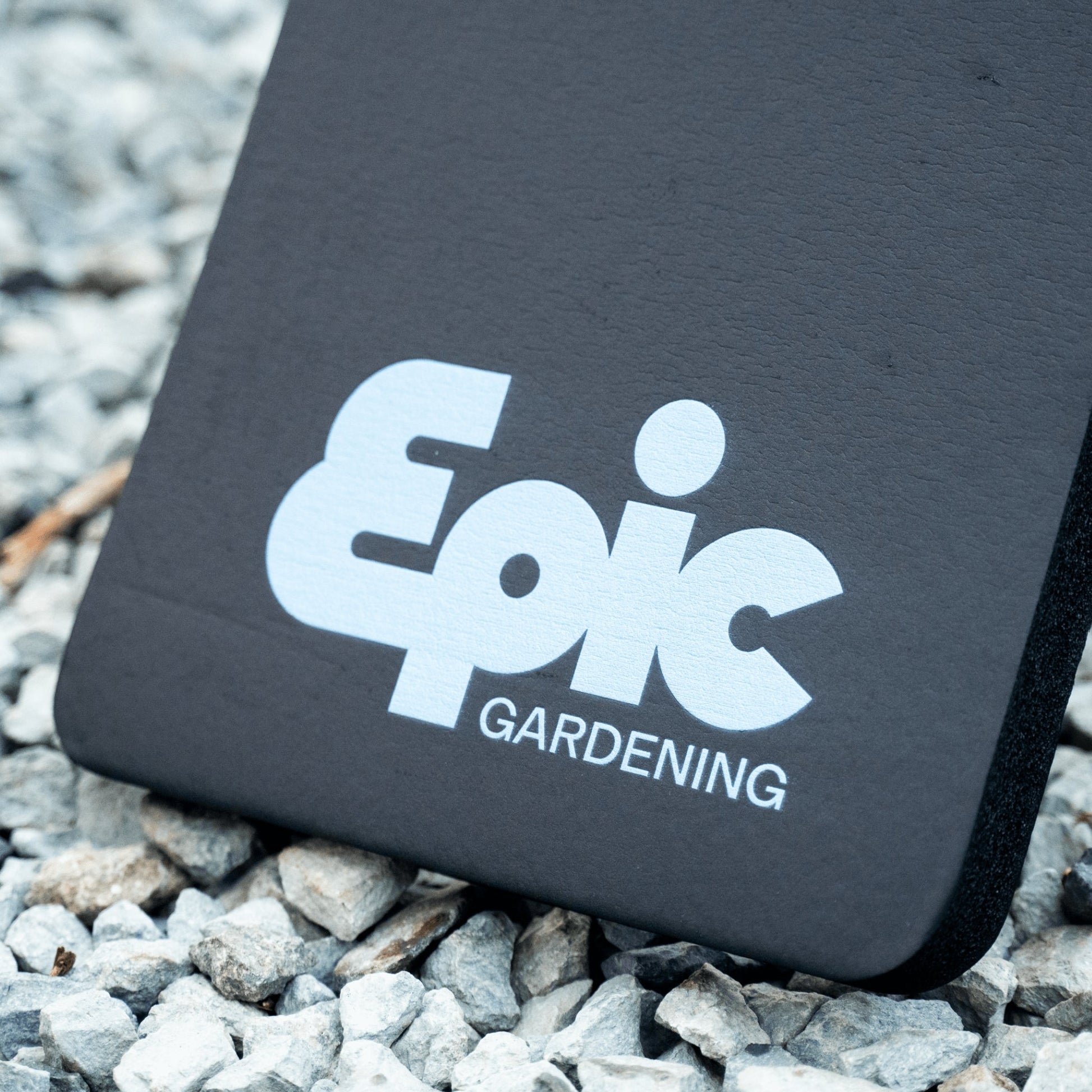 Kneepad for gardening resting on rocks. The pad is black, with Epic Gardening branding written at the bottom.