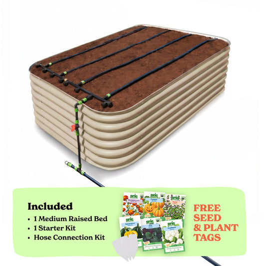 A raised garden bed in light clay color filled with soil, shown with drip irrigation tubing laid across the top. A light green promotional banner at the bottom lists included items: 1 29-inch tall medium raised bed, 1 starter kit, and hose connection kit, with a small image of seed packets and the text 'Free Seed & Plant Tags'.